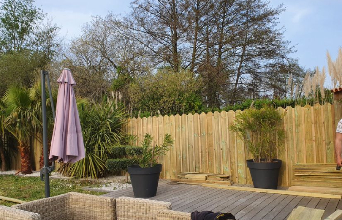 Aménagement extérieur avec terrasse bois, clôture et plantation paysagère réalisé par NC Paysages